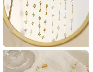 Détail du collier en or avec breloques d'étoiles et de croix colorées sur tissu blanc