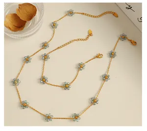 Detail of 18k gold plated floral necklace set with light blue crystal flower charms