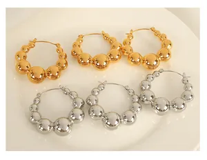 Detailed macro view of gold and silver chunky teardrop beaded hoop earrings on a tray