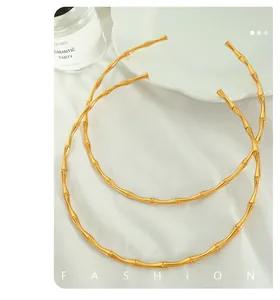 Nahaufnahme der goldenen Bambus-Halsreifen auf weißem Stoff für Damen-Mode-Stil
