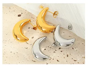 Close-up of polished C-shaped chunky earrings in gold and silver on a textured stone base