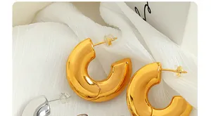 Macro detail of chunky C-shaped hoop earrings in polished gold and silver metallic finishes