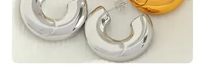 Close-up of polished C-shape hoop earrings in silver and gold with mirror finish
