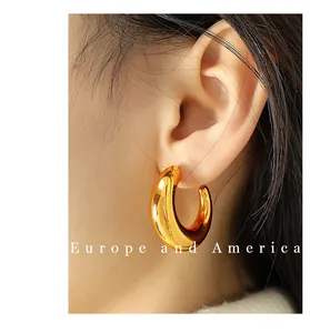 Close-up of polished C-shaped chunky gold earrings worn by a model in profile view