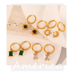 Detail of 18K gold plated earrings featuring opal sunburst and green gemstone charms