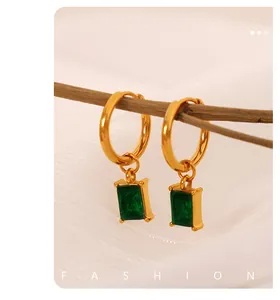 Detailed shot of 18K gold plated hoop earrings with emerald-cut green gemstone on wood