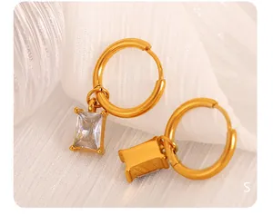 Detail of 18K gold plated hoop earrings with rectangular cat eye stones on textured fabric