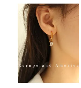 Close-up of 18K gold plated drop earring with rectangular zircon on woman's ear