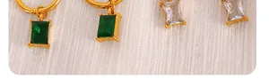 Macro detail of 18K gold plated earrings with emerald green and white cat eye stones
