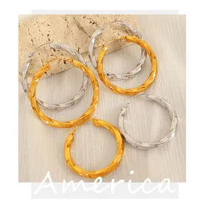Detailed close-up of chunky gold and silver twisted hoop earrings on stone background