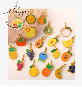 Detailed flat lay of colorful enamel fruit charms with golden rings on natural stone