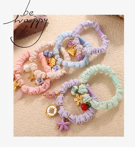 Detail of five macaron-colored scrunchies with various alloy and porcelain charms