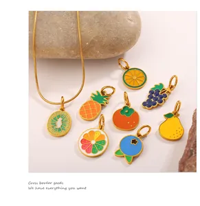 Detailed macro shot of summer fruit enamel charms with golden snake chain on stones