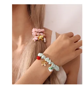 Detail of pink and green fabric scrunchies with golden flower and heart charms