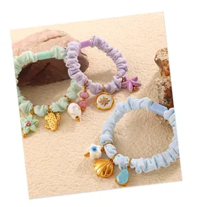 Close-up of pastel elastic scrunchies with cactus and star gold charms on sand