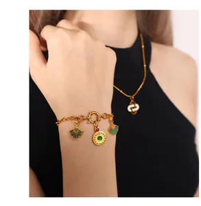 Detail van een gouden schakelarmband met groene emaille waaiers en een edelsteenhanger