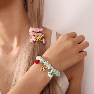 Sweet pink scrunchie with bow charm and mint green hair tie worn as a bracelet