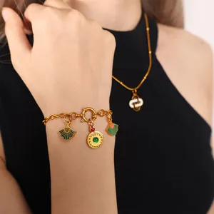 Gouden schakelarmband met groene waaiervormige hangers en een rood hart medaillon