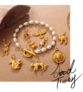 Detalle de una pulsera de perlas con colgantes de animales dorados y cierre de barra T
