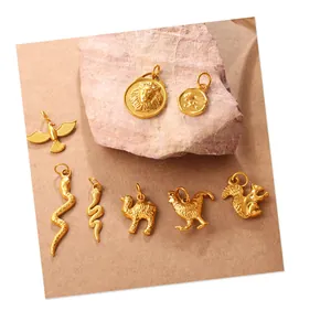 Detalle de ocho dijes de animales dorados que incluyen león, águila y serpiente para joyas DIY