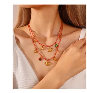 Detailed view of a double-layer red braided necklace with gold enamel animal charms