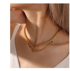 Close-up of layered gold necklace with cable and curb chains and a round toggle clasp