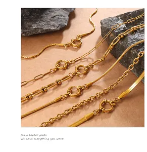 Detail shot of golden paperclip and snake chain necklaces with large round spring clasps