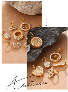 Macro shot of gold infinity and heart charms with embedded zircon stones on stone background