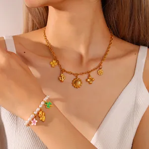 Goldene Kette mit Sonnenblumen-Anhängern und weißes Perlenarmband an einem Model