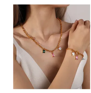 Close-up of a gold necklace and bracelet set with emerald, pink and white gemstones