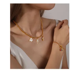 Close-up of gold chain jewelry set with bear, camera and I love London pendants