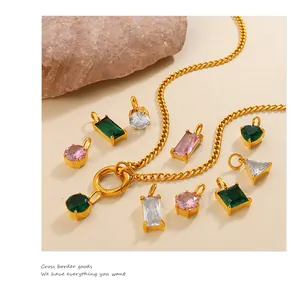 Close-up of geometric gold-plated zircon pendants in emerald and pink on stone base