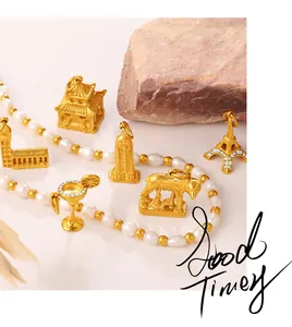 Detailed view of gold world landmark charms and pearl necklace on a textured stone surface