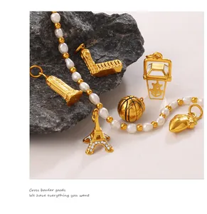 Detailed close-up of pearl chain with gold Eiffel Tower and cocktail themed charms
