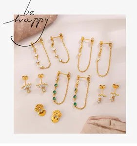 Detailed set of gold chain earrings with green marquise stones on a natural rock display