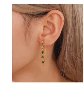 Detail of gold chain drop earring with white and emerald green zircon gemstones