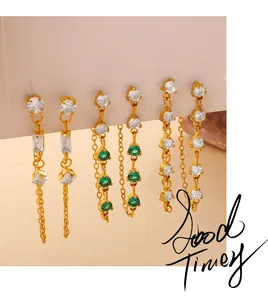 Detailed view of gold chain earrings set with white pearls and green gemstones