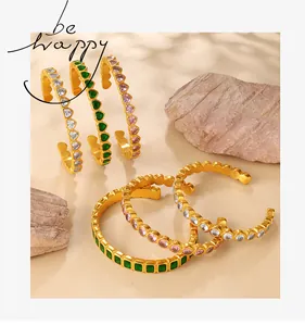 Detail of five-piece gold-plated cuff bracelets with emerald and pink cubic zirconia