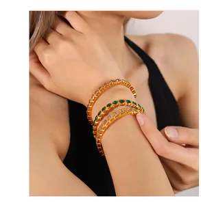 Detail of three-piece stackable gold bracelets with pink, green, and clear stones