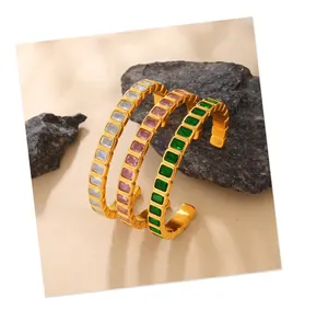 Macro detail of gold C-shaped cuff bracelets with colorful rectangular zircon stones