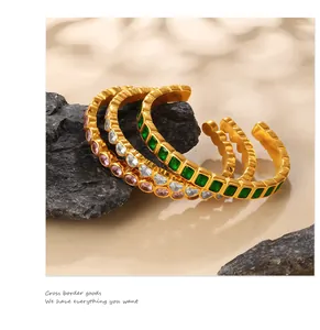 Detail of three gold cuff bracelets with pink, clear, and green square-cut zircons