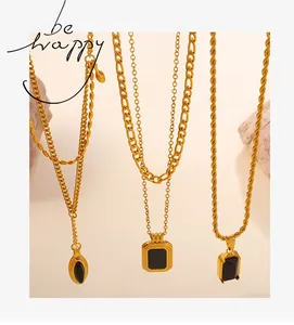 Detailed view of three gold necklaces with geometric black stone pendants and chains