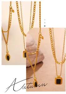 Close-up of vintage gold Figaro chain with black geometric pendants and layered textures