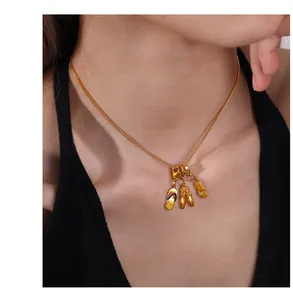 Gros plan d'un collier chaîne serpent dorée avec trois pendentifs en forme de chaussure