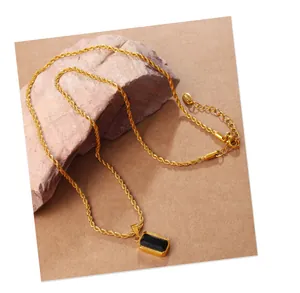 Macro detail of vintage gold rope chain with rectangular black gemstone pendant