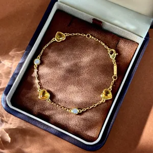Bracelet doré avec pierres jaunes en cœur et zircons ronds sur un coffret à bijoux