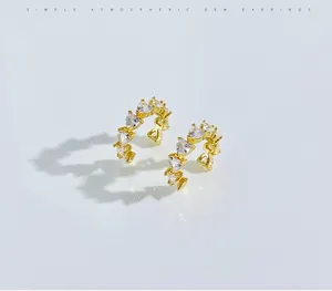 Detail of golden C-shaped earrings with heart-cut crystals and polished finish