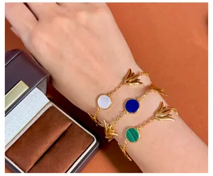 Detail von goldenen Tulpenanhängern mit weißer Muschel und Lapislazuli auf Armbändern