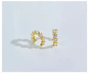 Detail of gold ear cuff featuring heart-shaped cubic zirconia in a C-shaped layout