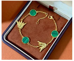 Details eines goldenen Tulpenanhängers und grüner Malachitscheibe am eleganten Armband